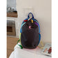Black color block backpack on a white bed, rainbow contrast trim and two stretch mesh side pockets