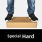 Kraft cardboard shoe box with a person in jeans and black sneakers standing on the closed box