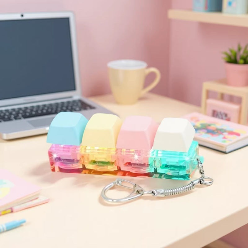 Pastel keycap fidget keychain on a pink desk with a laptop and mug