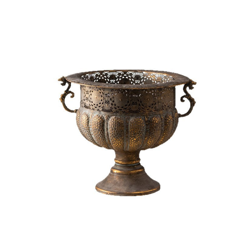 Antique style iron urn on a round foot with scroll handles and gold highlights on a white background