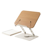 White frame reading stand with a wood grain board, two wire page holders and a swivel base beside a notebook