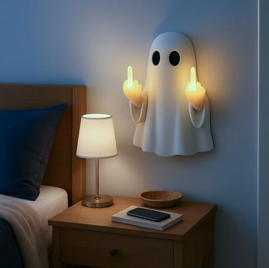Glowing ghost wall night light beside a bedside lamp in a dim blue bedroom at night