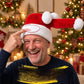 Smiling man in a red Santa hat touching the white band circled in red with the long tail raised by a Christmas tree