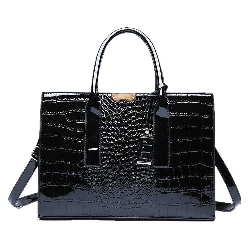 Black glossy croc pattern handbag with two top handles, buckled tab and shoulder strap, front view