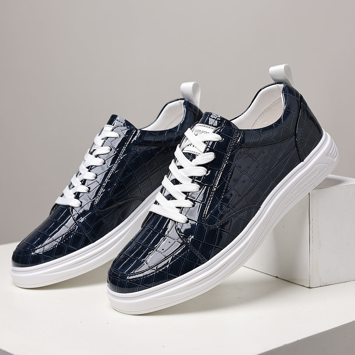 Navy blue embossed lace-up sneakers with white laces and sole on a white block, a color not offered as an option