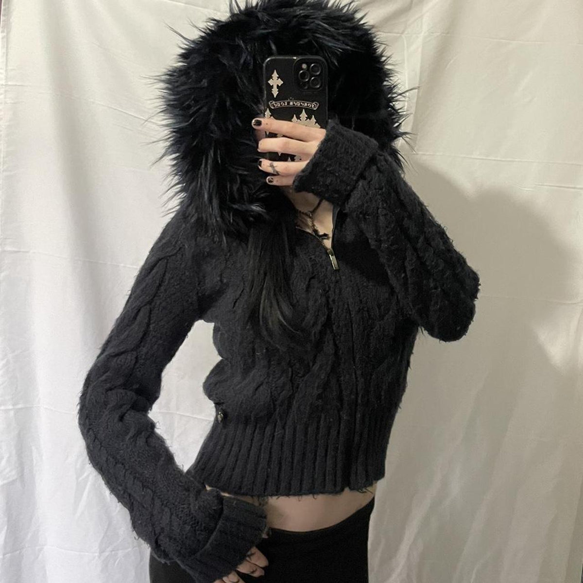Model taking a mirror photo in the black cable knit fur hooded zip cardigan with thumbhole cuffs
