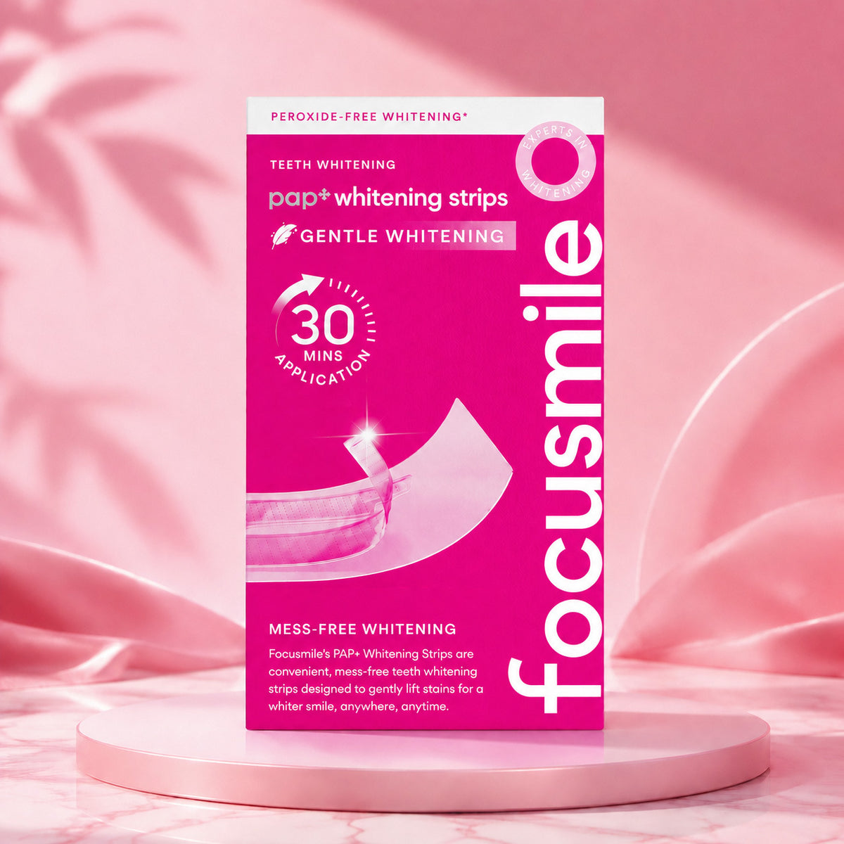 Pink Focusmile PAP+ whitening strips carton on a pink podium with soft pink satin in the background