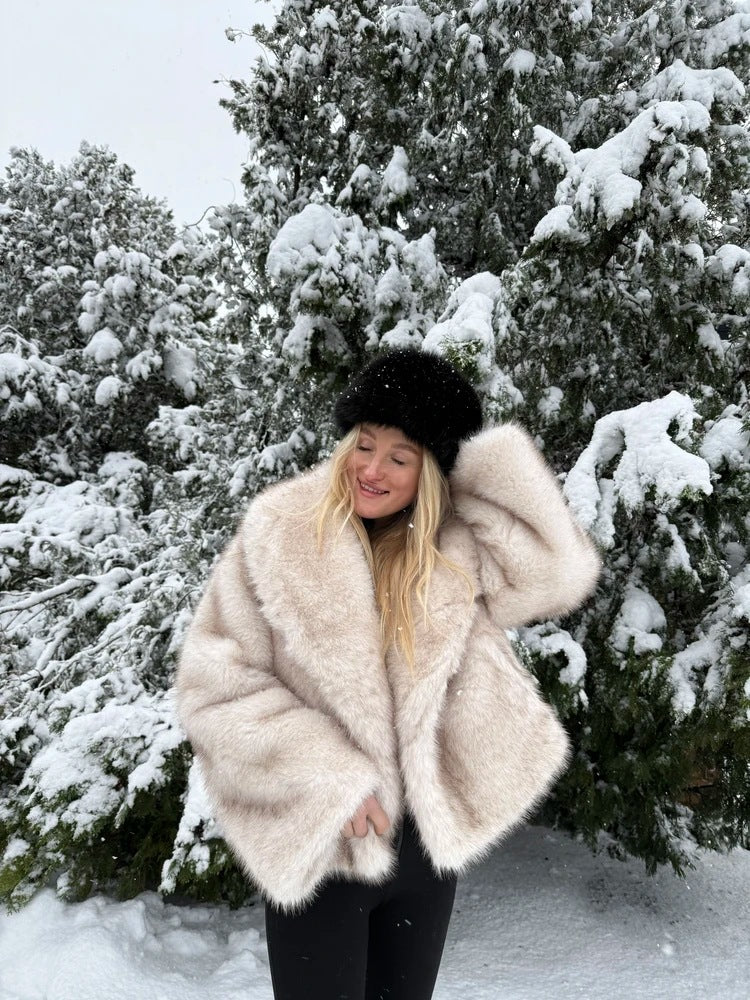 Cream vegan fur short jacket with shawl collar worn in the snow with a black hat