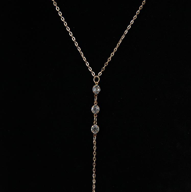 Close up of three round clear rhinestones in prong settings on a fine gold tone chain
