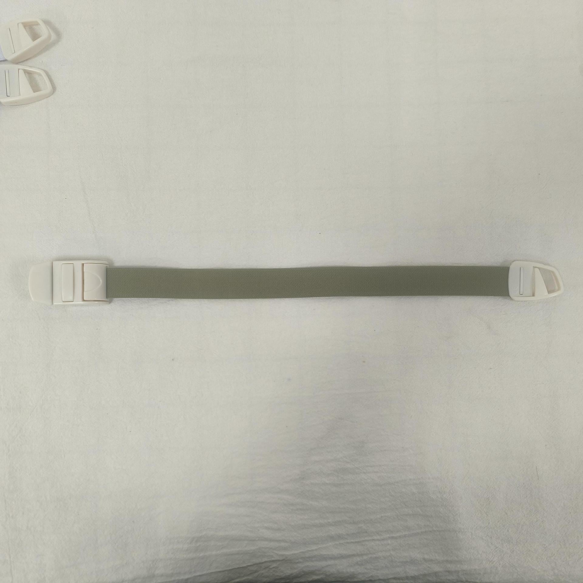 Single elastic quick release tourniquet band closed with its white snap buckle on a plain background