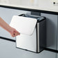 Hand swiping the white sliding lid of a stainless steel trash can open to show the trash bag inside