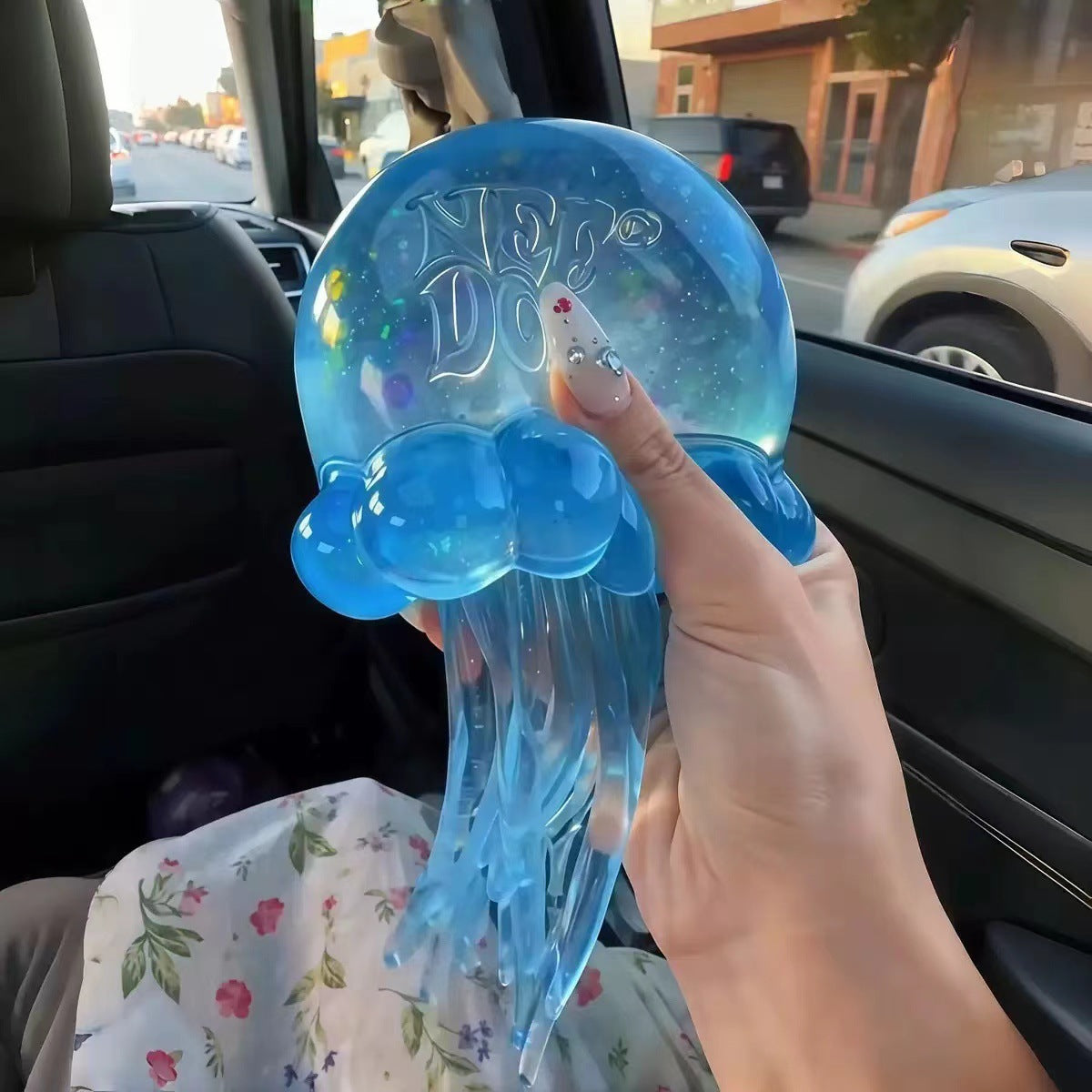 Blue NeeDoh Jelly Squish jellyfish in hand showing the NeeDoh name molded on the gel bell
