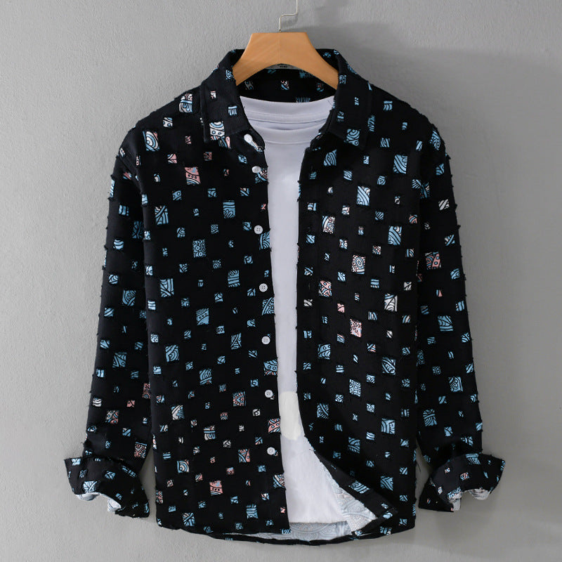 Black ground shirt jacket with cool toned frayed patch prints on a hanger