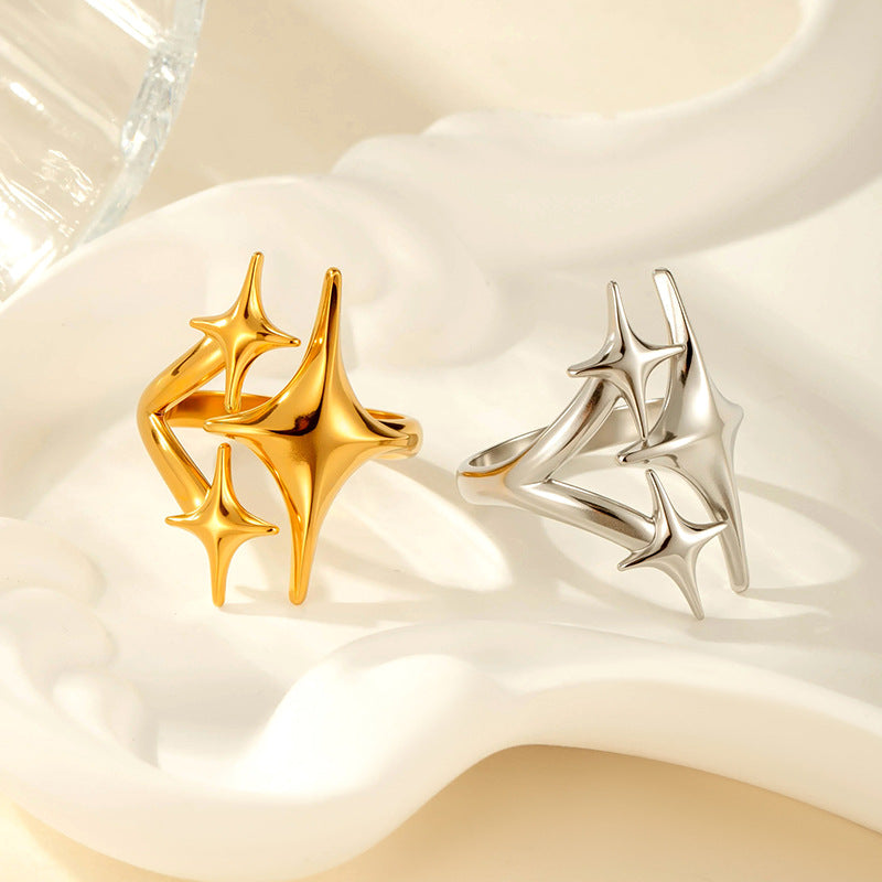 Gold and silver four-pointed star cluster rings resting on a white ripple dish
