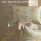 Silk pillowcase printed with pastel wildflowers on a beige ground, shown with a second case on a stone pedestal