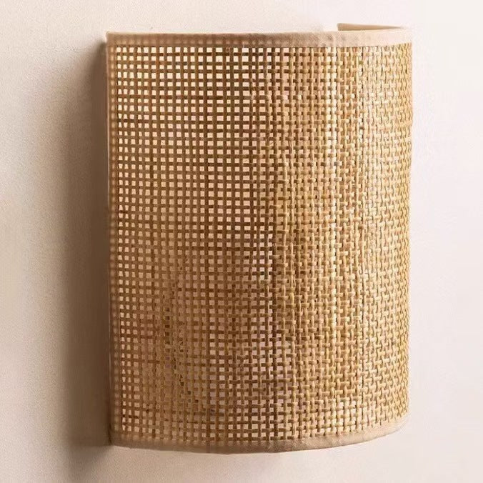 Second view of the half-cylinder wall lamp with an open woven cane shade on a light wall