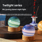 Two glass planet night lights on round wooden bases on a dark table beside a blue and white vase