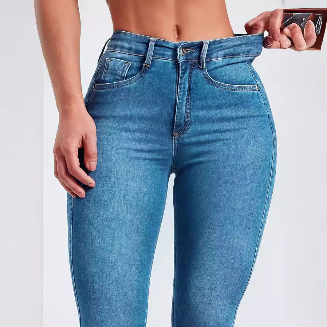 Close view of the waistband, zip fly and front pocket of denim blue high rise jeans