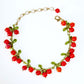Red imitation pearl beads bunched like berries with green leaves on a bracelet