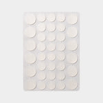 Sheet of thirty six translucent round hydrocolloid discs laid out on a plain grey background