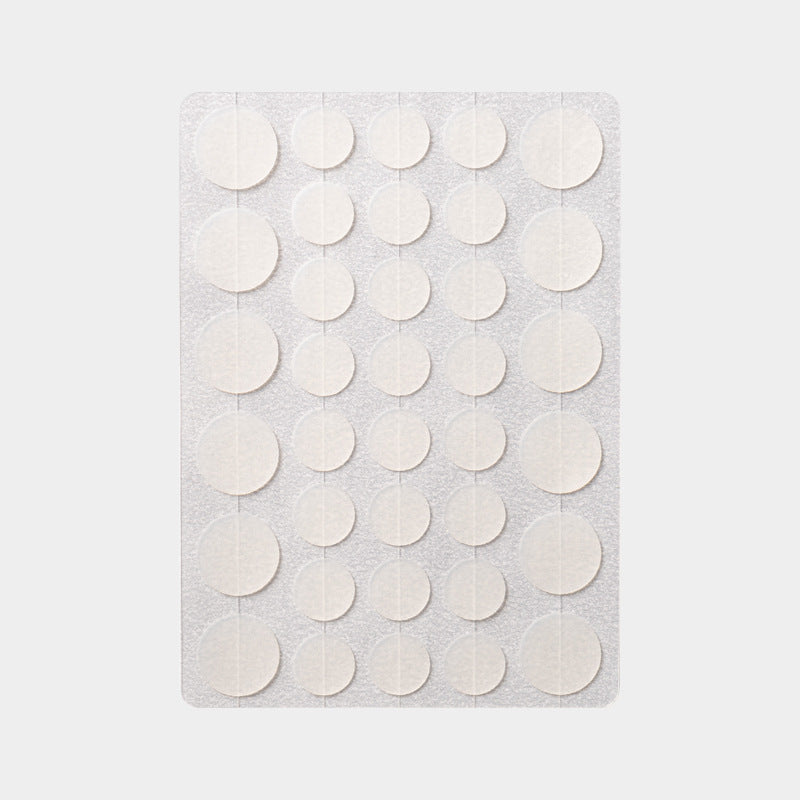 Sheet of thirty six translucent round hydrocolloid discs laid out on a plain grey background