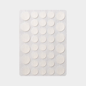 Sheet of thirty six translucent round hydrocolloid discs laid out on a plain grey background