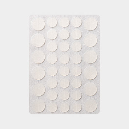 Sheet of thirty six translucent round hydrocolloid discs laid out on a plain grey background