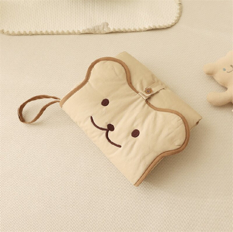 Quilted cotton changing pad unfolded with the bear-face flap and carry loop