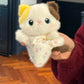 Squishy bean bag plush animal toy resting in a palm, brushed faux fur and printed cotton apron