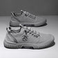 Pair of gray lace up canvas sneakers with a gray ribbed sole on a gray backdrop, one shoe seen from above