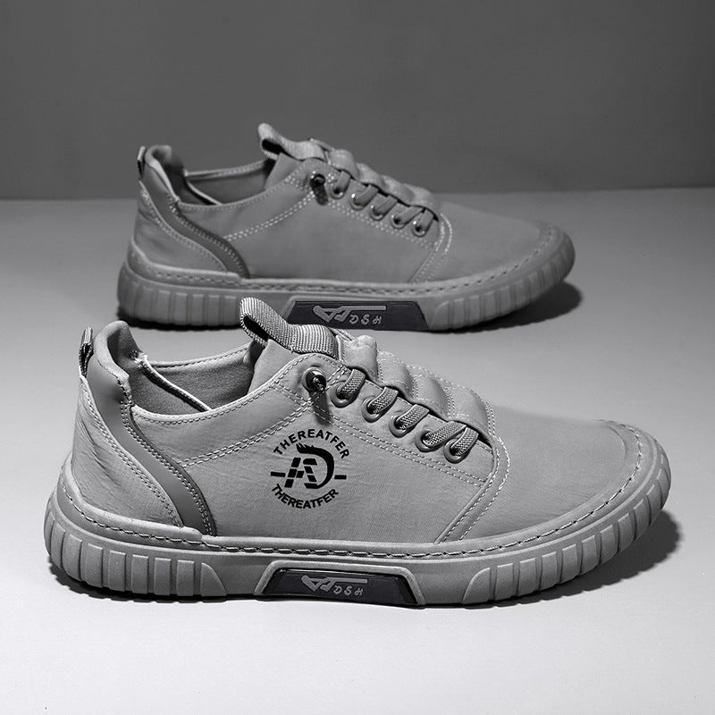 Pair of gray lace up canvas sneakers with a gray ribbed sole on a gray backdrop, one shoe seen from above