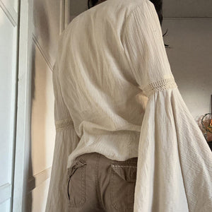Back view on the model showing the plain round neckline and the crinkle fabric falling from the shoulders