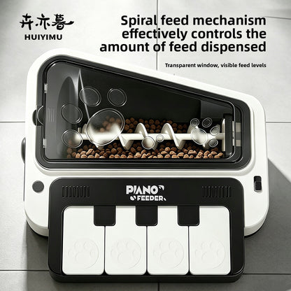 Black and white piano shaped pet feeder with transparent hopper showing a spiral feed mechanism and kibble