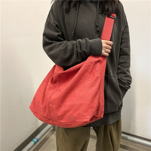 Red canvas crossbody bag worn across the body with a wide adjustable strap