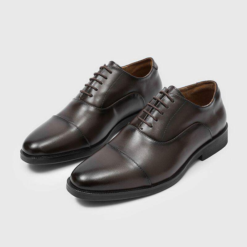 Pair of brown cap toe oxford dress shoes angled forward, tapered toes and dark low heel soles