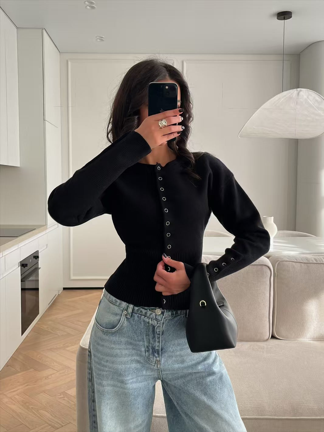 Black rib knit cardigan buttoned from the round neck to the hem over light jeans