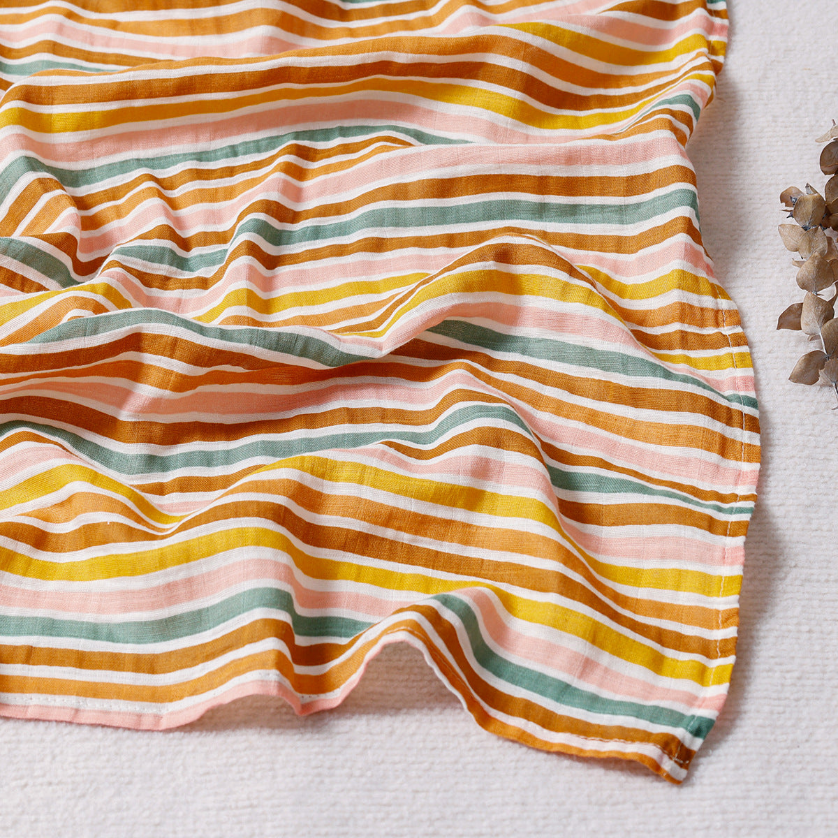 Folded cotton muslin swaddle blanket with a soft open weave and an even printed pattern