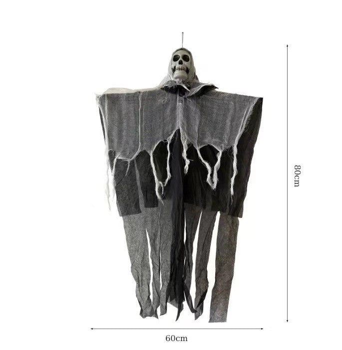 Orange fabric ghost hanging lamp lit in warm white beside a skull prop and a carved pumpkin