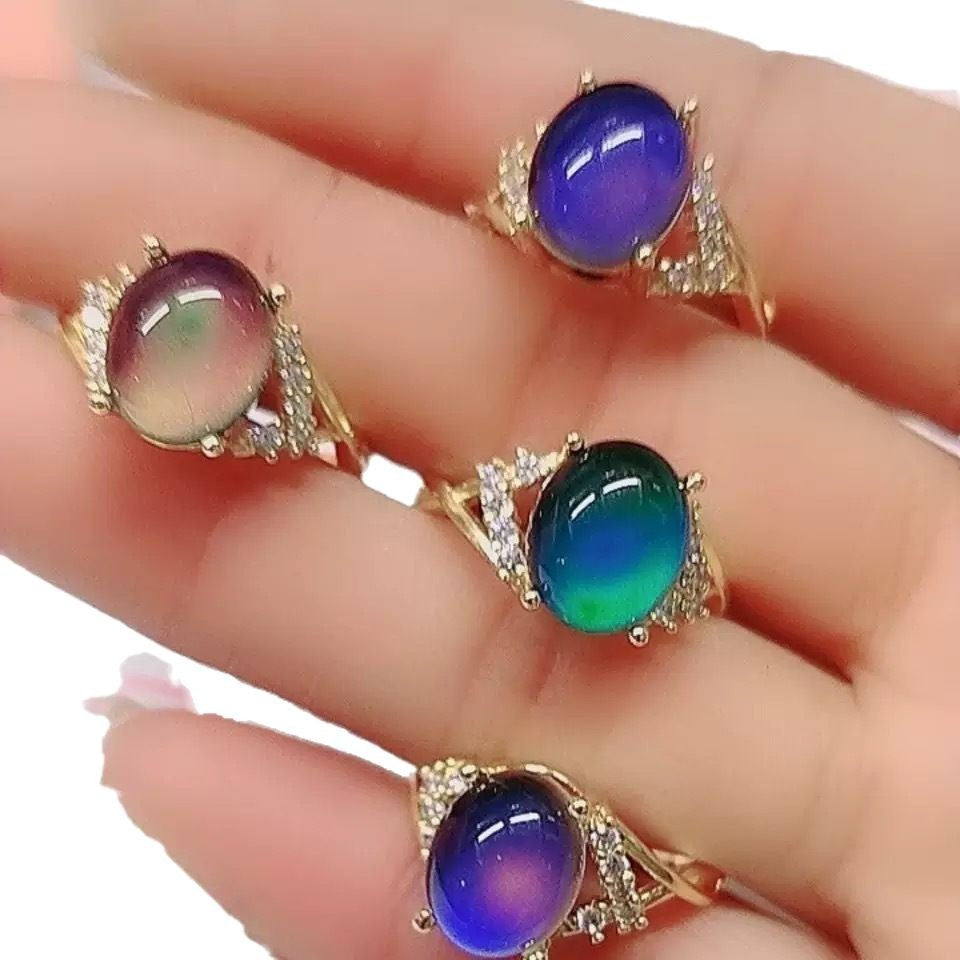 Gold-tone mood rings showing violet, blue and green oval stones with small clear accents on the shoulders