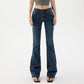 Close waist view of low rise dark denim jeans showing the button, zip fly and five pocket front
