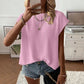 Woman wearing a pink round neck cap sleeve knit top with a relaxed drape and denim shorts