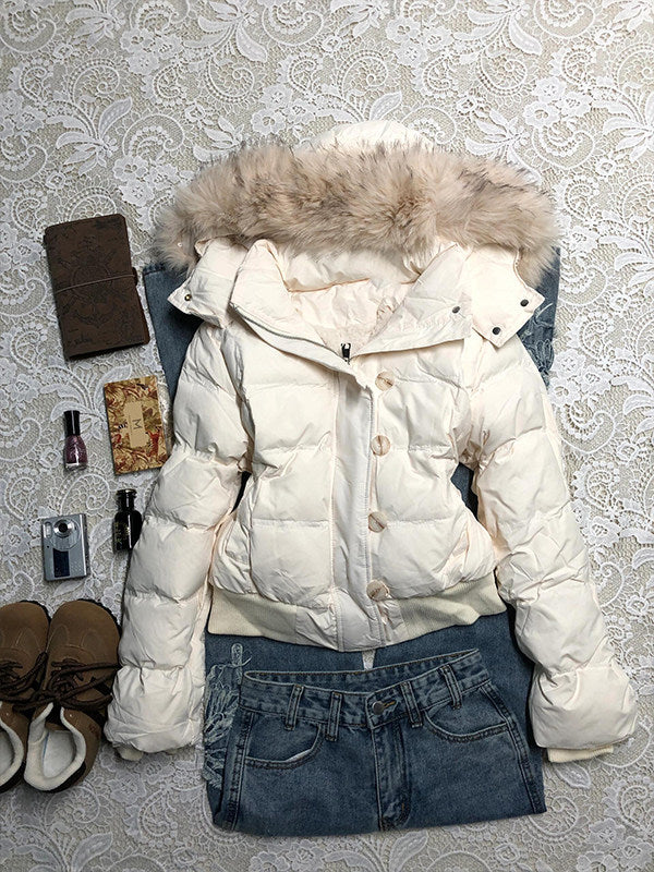 Cream white hooded quilted jacket with a furry hood trim laid flat on lace beside jeans and accessories