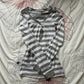 Gray and white striped henley top laid flat on a floral cloth showing the ribbed neckline and button placket
