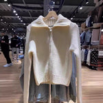 Cream chunky knit zip cardigan with wide ribbed collar hanging on a rack in a clothing store, front
