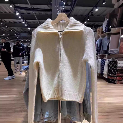 Cream chunky knit zip cardigan with wide ribbed collar hanging on a rack in a clothing store, front
