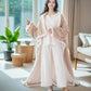 Smiling woman wearing the beige wearable blanket with sleeves and foot pockets in a bright living room