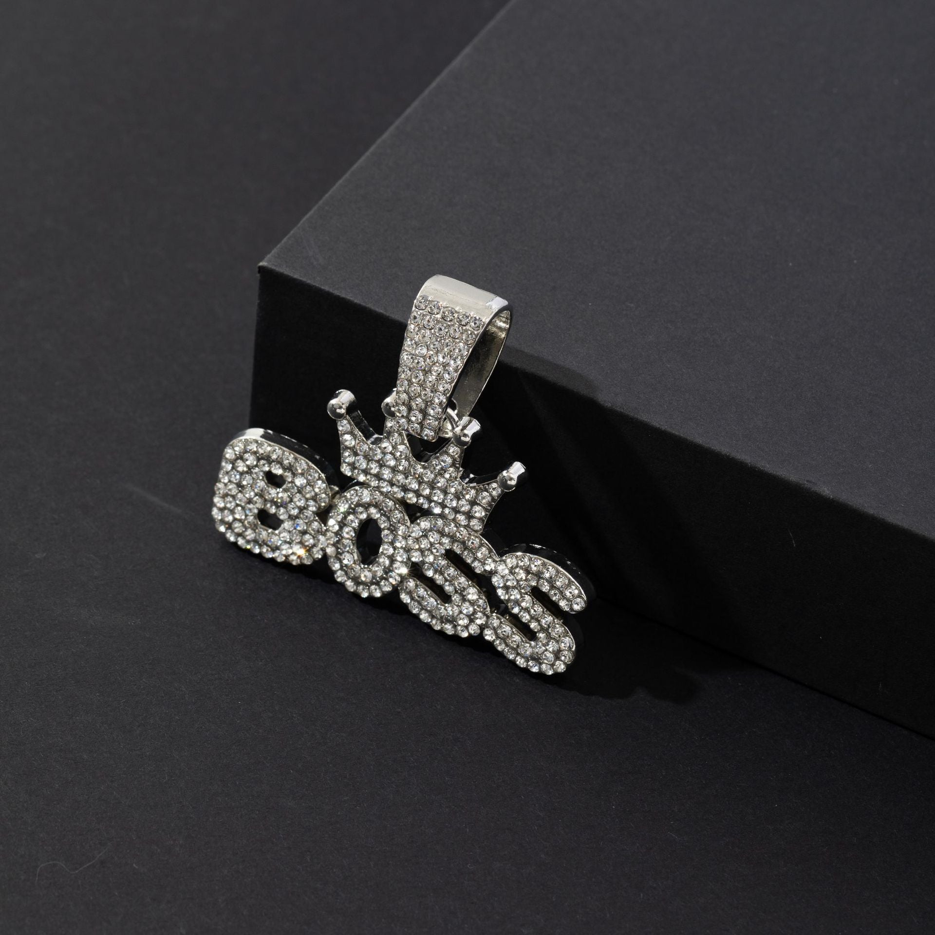 Crown pendant necklace with chain laid out beside packaging