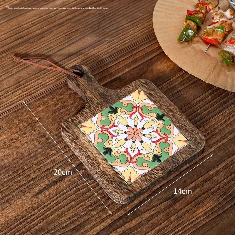 Wood trivet with a green and orange floral tile on planks, marked 20 cm by 14 cm