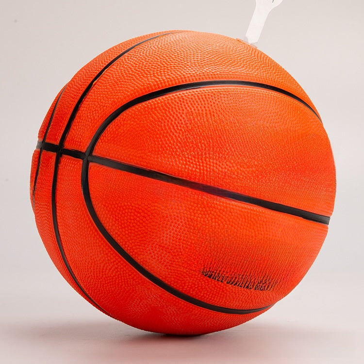 Orange rubber basketball tilted toward the camera, showing crossing black channels and a pebbled cover