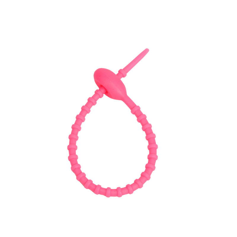 Tadpole silicone tie looped around a wrist to show how flexible the strap is
